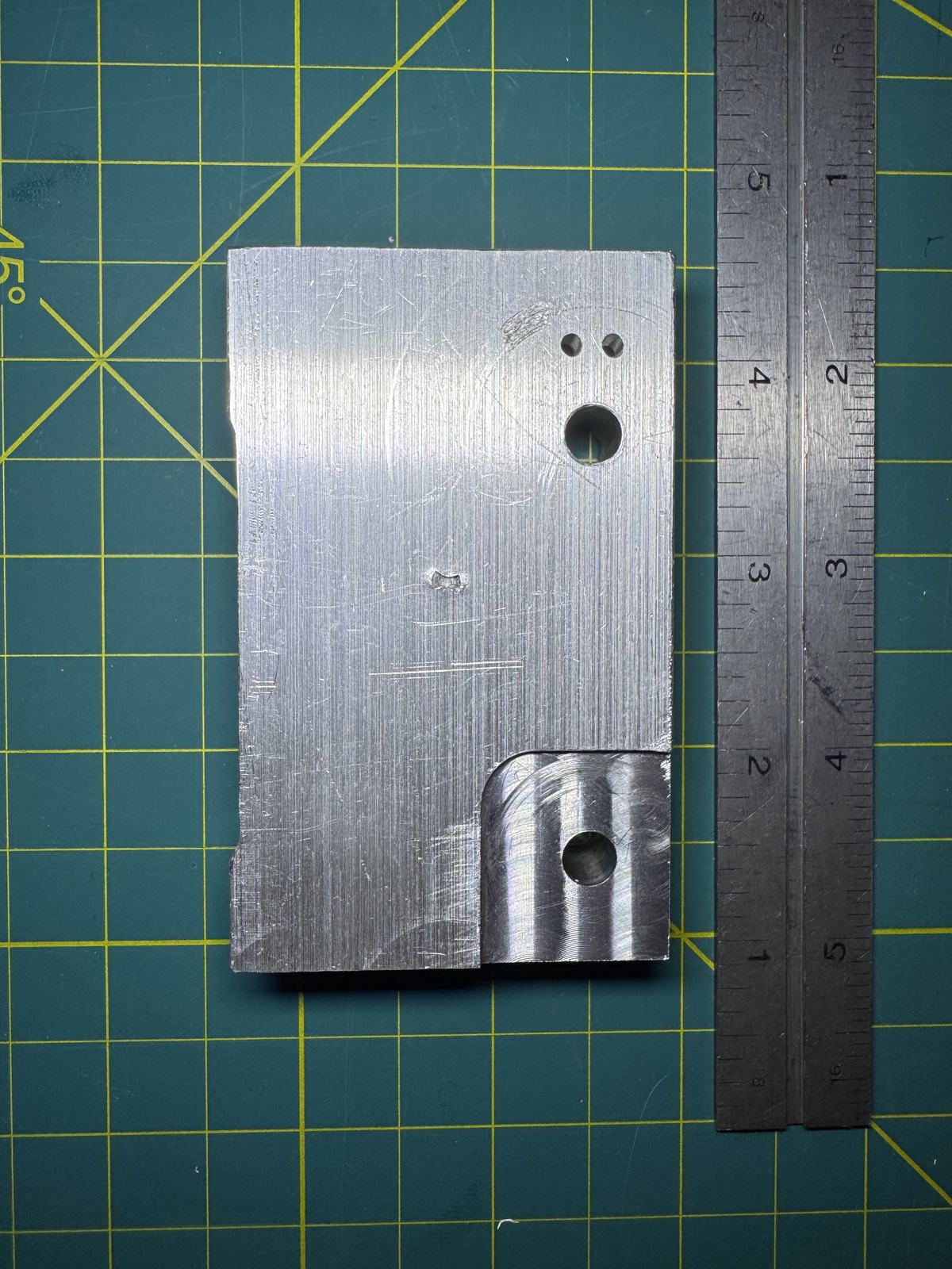 Manually machined aluminum cylinder block next to a ruler for scale